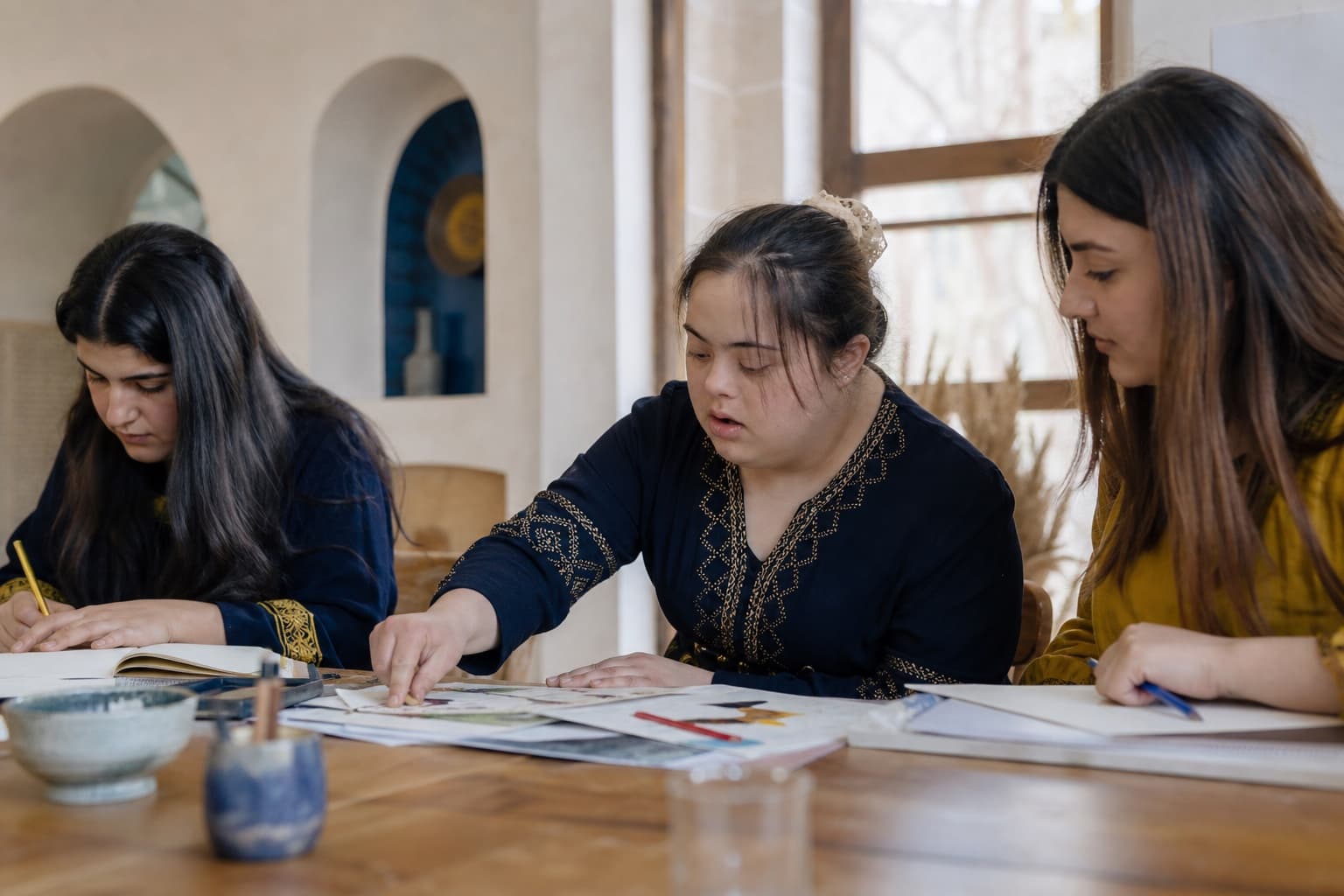 A Kurdish young woman with Down syndrome works alongside peers in a creative workshop.